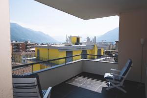einen Balkon mit 2 Stühlen und ein gelbes Gebäude in der Unterkunft Schöne Ferienwohnung mit Panoramablick in Locarno