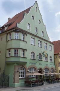 ein großes grünes Gebäude mit Tischen davor in der Unterkunft Hotel PIAZZA in Dinkelsbühl