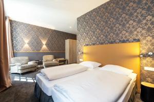 a hotel room with a bed and a chair at Hotel Deutschherrenhof in Zeltingen-Rachtig
