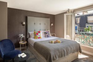 a bedroom with a bed with a blue chair and a window at Hotel Opéra Marigny in Paris