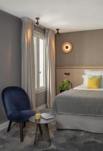 a bedroom with a bed and a blue chair at Hotel Opéra Marigny in Paris
