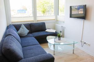 un soggiorno con divano blu e tavolo in vetro di Haus-Strandburg-Sanddorn a Dahme