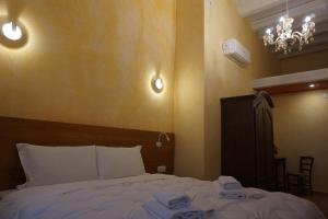 um quarto com uma cama com lençóis brancos e um lustre em PALAZZO FULGHER em Cagliari