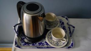 a tea kettle and two cups on a table at Nyx & Iris in Zasa