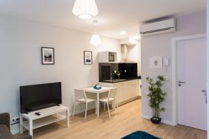 Una sala de estar con un televisor y una mesa con sillas. en Funchal Village Studios, en Funchal