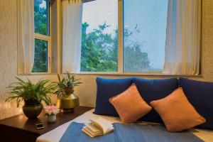 a couch with pillows and a table and windows at EL Lodge by StayVista - Pool, lawn, and a charming gazebo for your perfect getaway in Lonavala