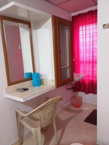 a bathroom with a chair and a sink and two mirrors at Anandan Tourist Home in Varkala