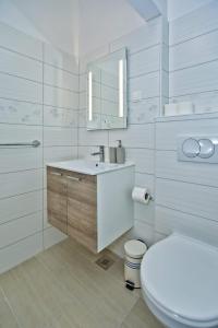 a white bathroom with a toilet and a sink at Apartments Magdalena in Hvar