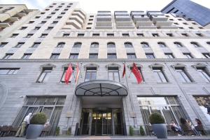 a building with red flags in front of it at Ramada Hotel & Suites by Wyndham Yerevan in Yerevan