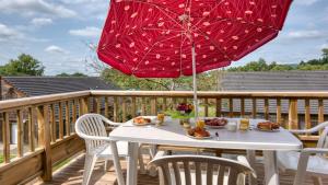 una mesa de patio con una sombrilla roja en una terraza en Vacancéole - Residence le Domaine du Bosquet, en Égletons