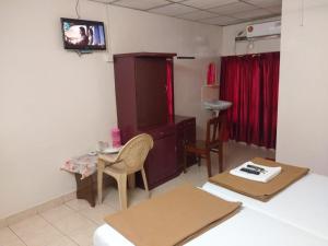a room with a bed and a desk and a tv at Anandan Tourist Home in Varkala