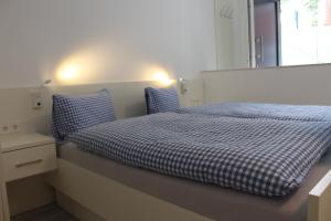Schlafzimmer mit einem Bett mit blauer und weißer Bettwäsche und einem Fenster in der Unterkunft Haus Etzold in Norderney
