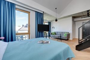 a bedroom with a blue bed and a living room at Pogodna Apartments in Sopot