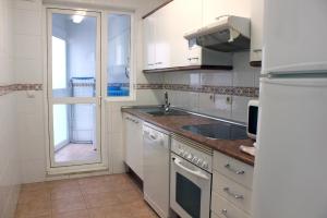 een keuken met witte kasten, een wastafel en een raam bij El FARO 2 in Estepona