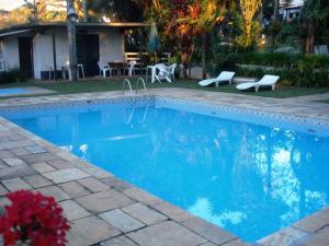 a blue swimming pool with two chairs and a house at Hotel Fazenda Bandeirantes in Ibiúna