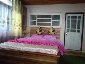 Schlafzimmer mit einem Bett mit rosa Bettwäsche und einem Fenster in der Unterkunft Bethany Homestay in Kalimpong