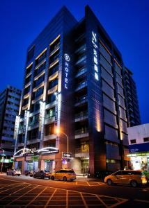 un edificio alto con coches estacionados frente a él en Skyone Hotel en Kaohsiung