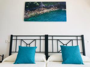 um quarto com uma cama com almofadas azuis em Hostal la Tarayuela em Barbate