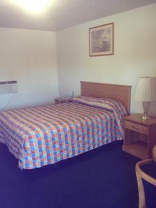 1 dormitorio con cama, lámpara y mesa en Hacienda Motel, en San Jacinto