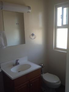 een badkamer met een wastafel, een toilet en een spiegel bij Hacienda Motel in San Jacinto