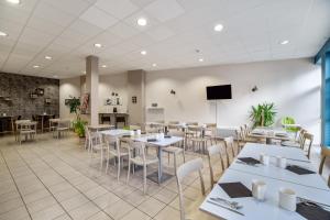 a restaurant with white tables and chairs and a flat screen tv at Appart'City Niort in Niort