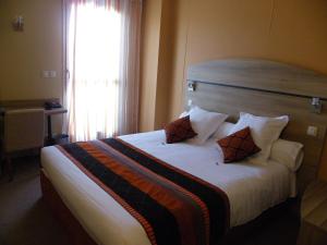 a hotel room with a bed with pillows and a window at Les Étoiles Du Forez in Montbrison