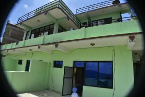a green building with a balcony on top of it at Hotel Greenland in Nagarkot