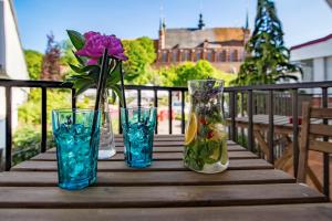 a wooden table with four glass vases and a purple flower at Pod Wzgórzem Bed & Breakfast in Frombork
