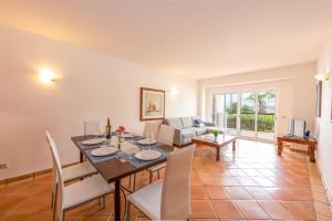 a dining room with a table and chairs and a couch at Clube Alvor Ria - Prime Residence in Alvor