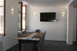 a dining room with a table and a tv on the wall at Riders Apartments in Le Bourg-dʼOisans