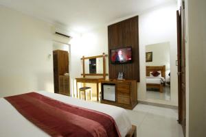 a hotel room with a bed and a television at Swastika Guesthouse Sanur in Sanur