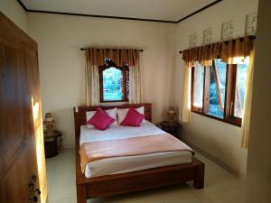 a bedroom with a bed with pink pillows on it at Taman Sari Tagtag in Sanur