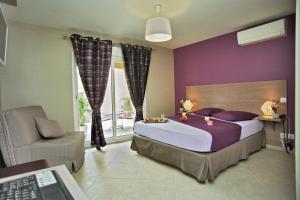 ein Schlafzimmer mit einem Bett mit lila Wänden und einem Stuhl in der Unterkunft Hôtel l'Anvia in Bollène