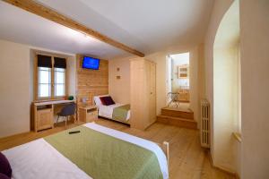 Schlafzimmer mit einem Bett, einem Schreibtisch und einem TV in der Unterkunft B&B Antica Residenza Centro Storico in Tirano