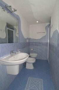a blue and white bathroom with a sink and a toilet at Sardegna Beach Cala Reale in Santa Marinella +31 photos