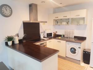 cocina con encimera y lavadora en 3 Bed Luxury Town Center Apartment with 50 inch 4K TV (Netflix & NowTV Ent. Pass) en Northampton