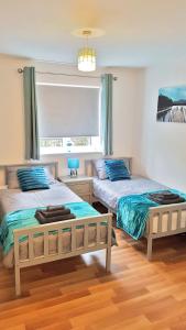 ein Schlafzimmer mit zwei Betten und einem Fenster in der Unterkunft 3 Bed Luxury Town Center Apartment with 50 inch 4K TV (Netflix & NowTV Ent. Pass) in Northampton