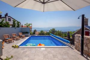 a swimming pool with an umbrella on a patio at Villa LETA, luxurious 5 stars villa in a green oasis with fitness, heated pool, playground & barbecue, Kvarner in Hreljin