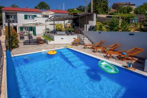 a swimming pool with two lawn chairs and a toy kayak at Villa LETA, luxurious 5 stars villa in a green oasis with fitness, heated pool, playground & barbecue, Kvarner in Hreljin