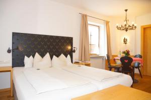 Schlafzimmer mit einem großen weißen Bett mit einem schwarzen Kopfteil in der Unterkunft Hotel & Gasthof Fraundorfer in Garmisch-Partenkirchen