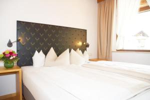 a bedroom with a white bed with a black headboard at Hotel & Gasthof Fraundorfer in Garmisch-Partenkirchen