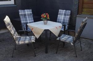 a table and four chairs with a vase of flowers on it at Ferienhaus am Rennsteig in Schmiedefeld am Rennsteig