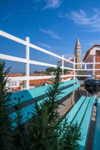 a blue bench with a clock tower in the background at Apartment Sebastijan in Piran