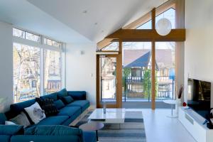 a living room with a blue couch and a large window at Hakuba White Fox Chalet in Hakuba