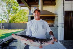 un homme tenant un gros poisson dans sa main dans l'établissement Santa Rosa Pantanal Hotel, à Pôrto Jofre