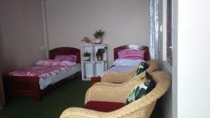 een slaapkamer met 2 bedden en een rieten stoel bij Bethany Homestay in Kalimpong