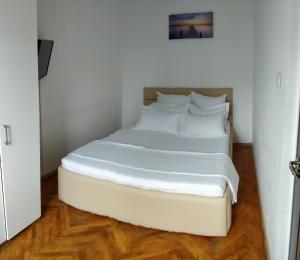 コンスタンツァにあるConstanta City Apartmentのウッドフロアの客室で、白い大型ベッド1台が備わります。