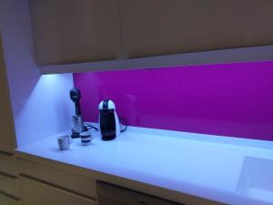 a kitchen counter with a pink wall and two coffee cups at Gouves Beach Boutique Apartment in Gouves +107 photos