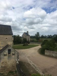 an old stone house with a dirt road in front at Boutons d'or in Tierceville