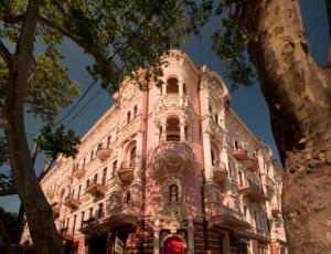 een roze gebouw met bomen ervoor bij Hotel Bristol in Odessa